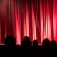 An audience watching a stage with a forum theatre performance