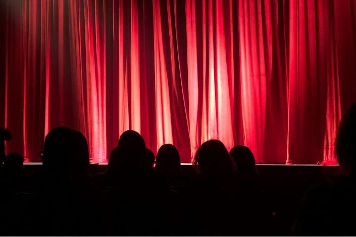 An audience watching a stage with a forum theatre performance